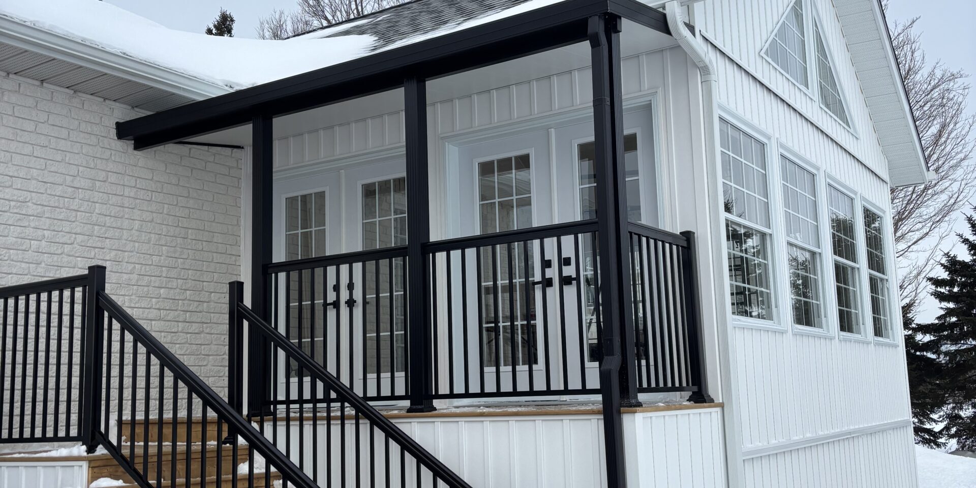 422FC51F-4DEF-4560-A992-25B6C4FE52E2_L0_001-2025-02-14, 1_28_05 PM White house with black roof, trough and aluminum railing. snow covered
