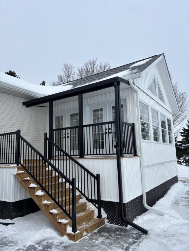 422FC51F-4DEF-4560-A992-25B6C4FE52E2_L0_001-2025-02-14, 1_28_05 PM White house with black roof, trough and aluminum railing. snow covered